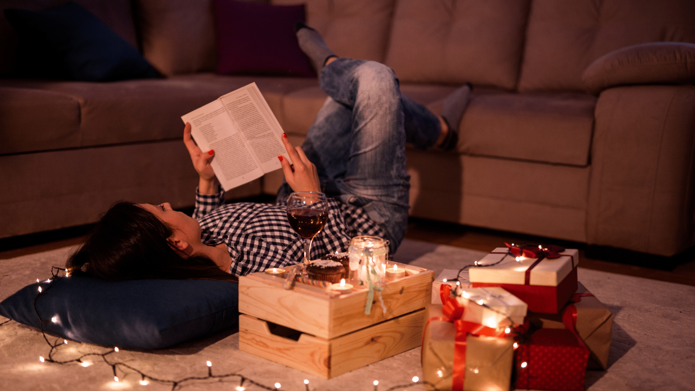 Person relaxing with a book at Christmas there are some candles and fairy lights